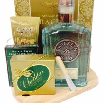 The Boss’ Favorite Gin Gift Basket holds a bottle of Brooklyn Gin, cheese spread, crackers, and chocolates on a wooden cutting board